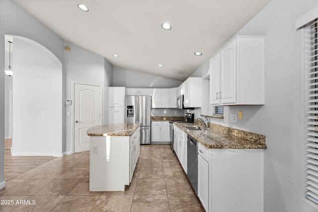 kitchen featuring light tile patterned floors, white cabinetry, appliances with stainless steel finishes, dark stone counters, and a kitchen island