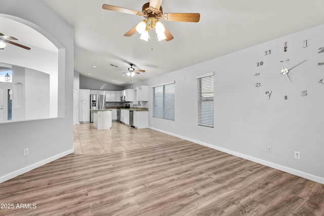 unfurnished living room featuring light wood-type flooring, ceiling fan, and vaulted ceiling