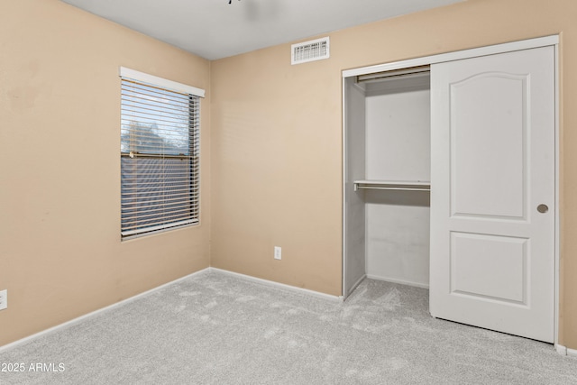 unfurnished bedroom with light carpet and a closet