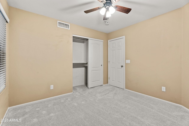 unfurnished bedroom featuring ceiling fan, a closet, and light colored carpet