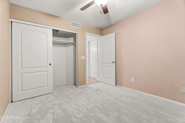 unfurnished bedroom featuring ceiling fan, a closet, and light carpet