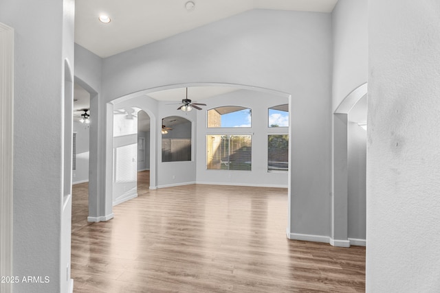 unfurnished living room with ceiling fan, wood-type flooring, and vaulted ceiling