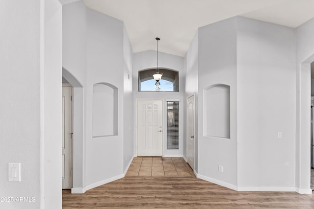 foyer entrance featuring wood-type flooring and high vaulted ceiling