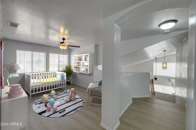 living room featuring ceiling fan, light hardwood / wood-style flooring, a textured ceiling, and vaulted ceiling