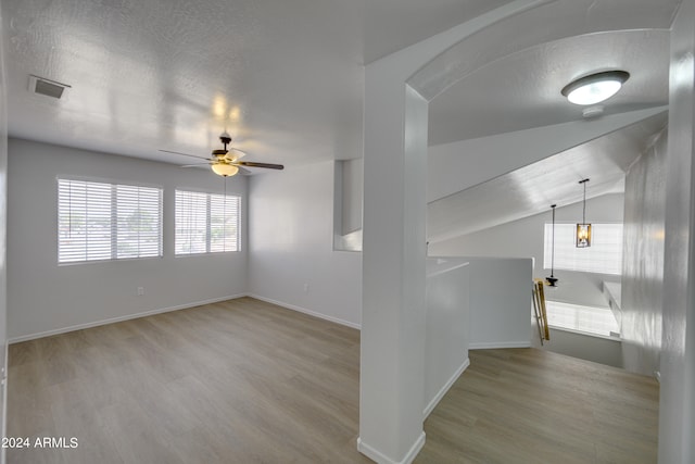 interior space with vaulted ceiling, a textured ceiling, and light wood-type flooring