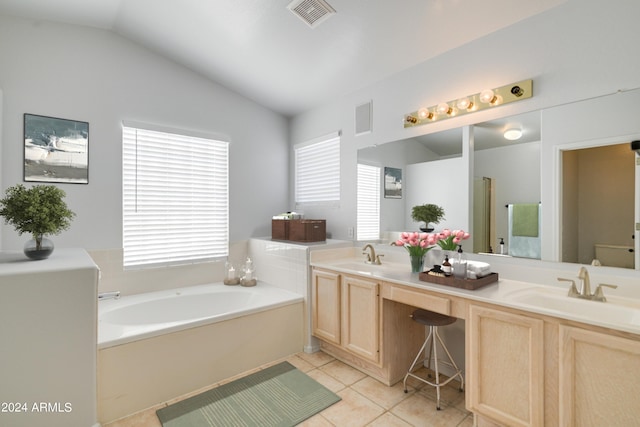 bathroom with lofted ceiling, tile patterned flooring, vanity, toilet, and a bath