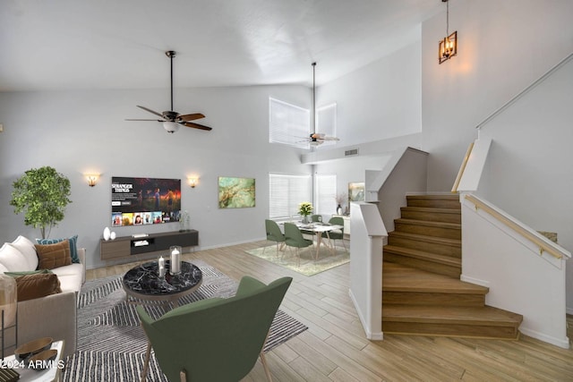 living room with high vaulted ceiling, ceiling fan, and light hardwood / wood-style flooring