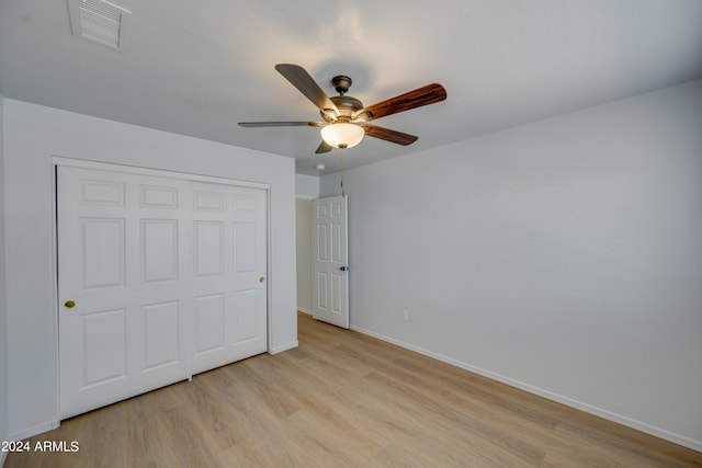 unfurnished bedroom with ceiling fan, a closet, and light wood-type flooring