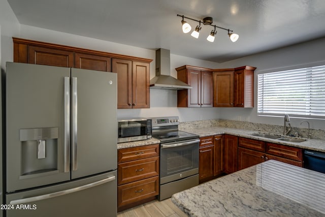 kitchen with sink, wall chimney exhaust hood, light stone countertops, and stainless steel appliances