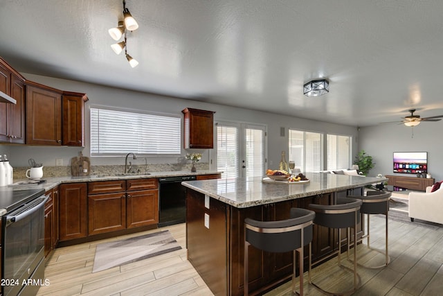 kitchen featuring black dishwasher, a breakfast bar area, sink, a center island, and electric range