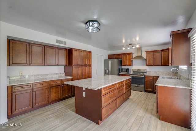 kitchen featuring sink, appliances with stainless steel finishes, a center island, light hardwood / wood-style floors, and wall chimney exhaust hood