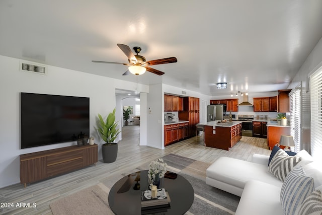 living room with a wealth of natural light, ceiling fan, and light wood-type flooring