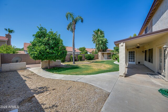 view of yard featuring ceiling fan, a storage unit, and a patio area