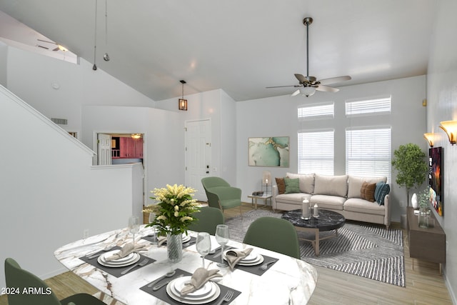 dining room with a towering ceiling, light hardwood / wood-style floors, and ceiling fan