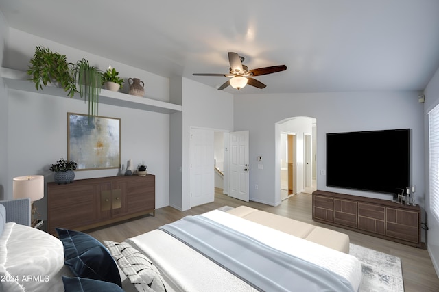 bedroom featuring vaulted ceiling, ceiling fan, light hardwood / wood-style floors, and ensuite bath