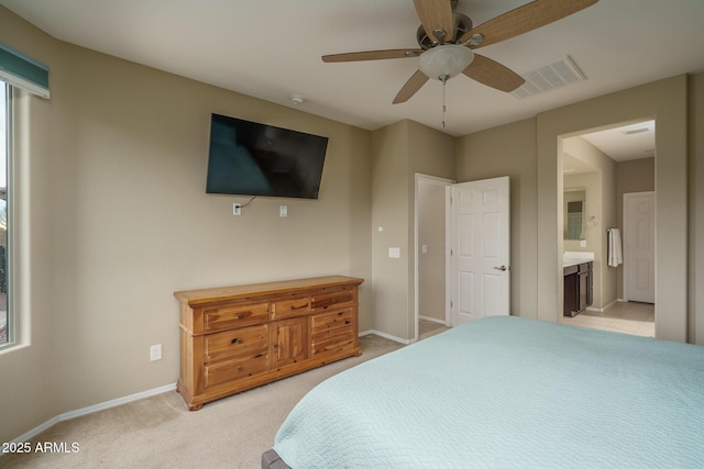 bedroom featuring visible vents, baseboards, ensuite bath, ceiling fan, and light colored carpet