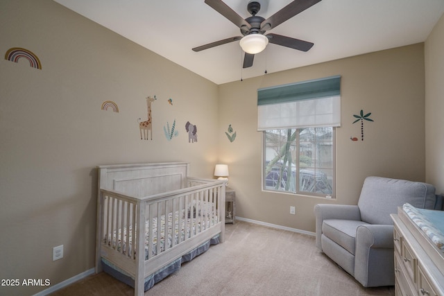 bedroom with carpet flooring, a crib, baseboards, and a ceiling fan