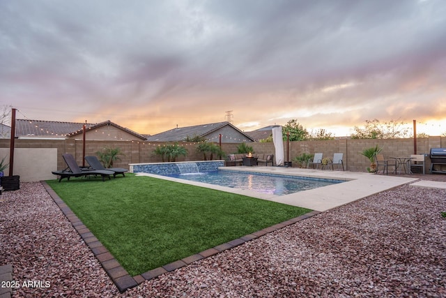 pool at dusk featuring a yard, a patio, a fenced in pool, and a fenced backyard