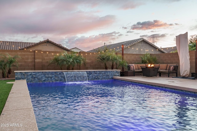 pool at dusk with an outdoor living space with a fire pit, a patio area, a fenced backyard, and a fenced in pool