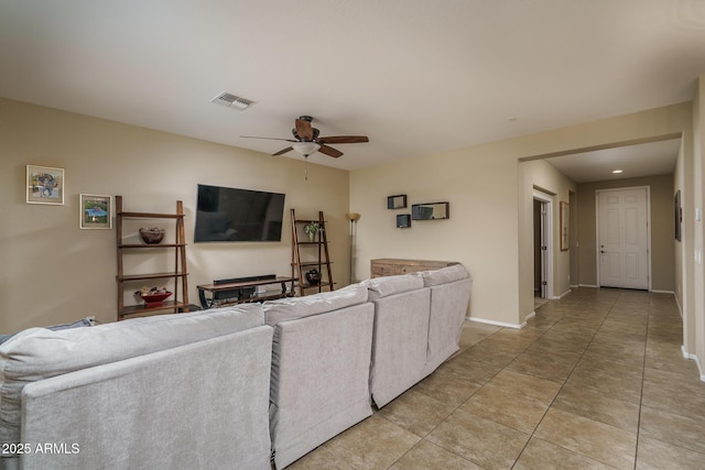 living area featuring light tile patterned floors, a ceiling fan, visible vents, and baseboards