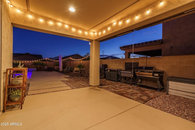 patio at twilight featuring a grill and a fenced backyard