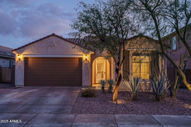 view of front of house with concrete driveway, a tiled roof, an attached garage, and stucco siding