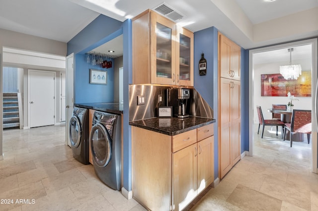 kitchen with pendant lighting, washing machine and dryer, dark stone countertops, and light brown cabinetry