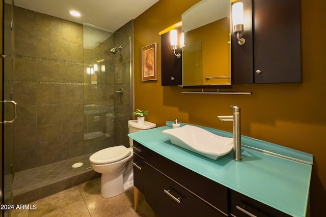 bathroom with tile patterned flooring, vanity, toilet, and a shower with door