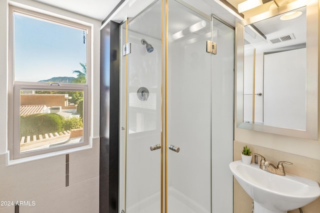 bathroom with a shower with door and sink