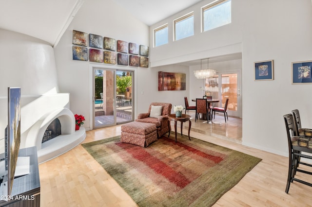 living room featuring a large fireplace, high vaulted ceiling, a notable chandelier, and hardwood / wood-style flooring