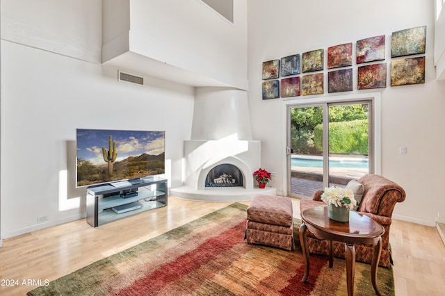 living room featuring a towering ceiling, hardwood / wood-style floors, and a large fireplace