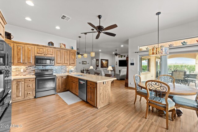 kitchen featuring visible vents, a sink, appliances with stainless steel finishes, a peninsula, and light countertops