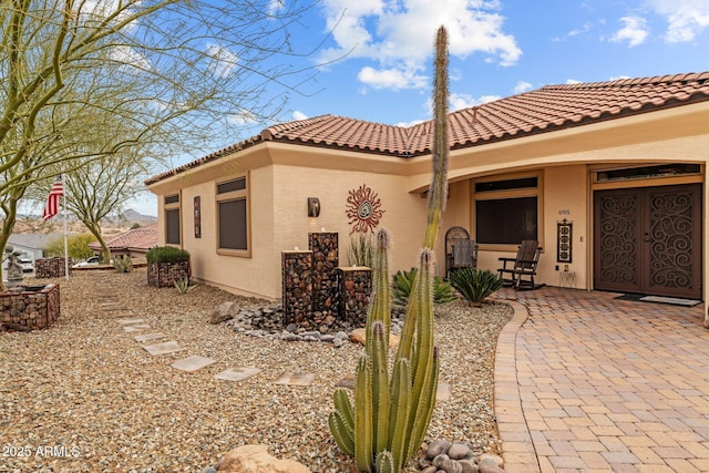 back of property with stucco siding and a tile roof