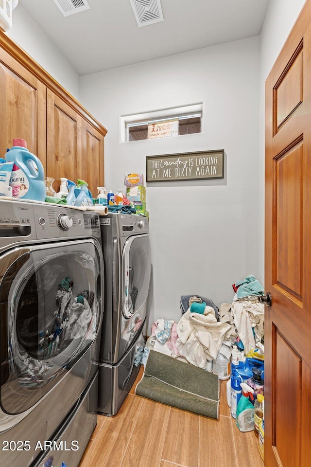 laundry room with wood finished floors, cabinet space, separate washer and dryer, and visible vents