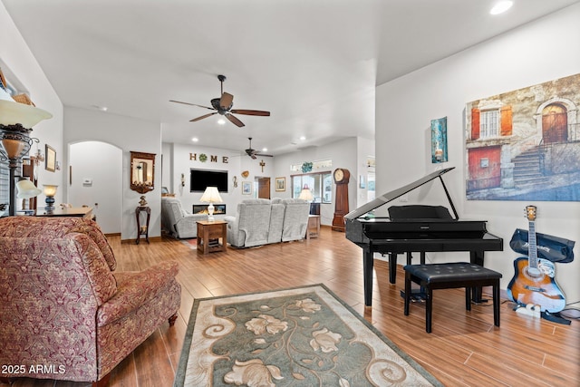 living area featuring arched walkways, recessed lighting, ceiling fan, and wood finished floors