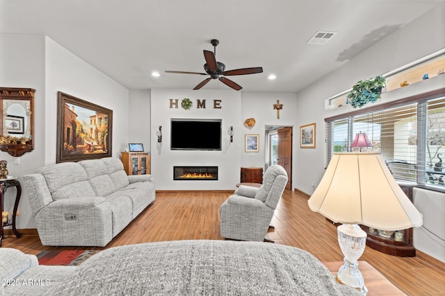 living room with visible vents, ceiling fan, recessed lighting, wood finished floors, and a glass covered fireplace