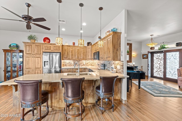 kitchen with a sink, tasteful backsplash, appliances with stainless steel finishes, a peninsula, and light stone countertops