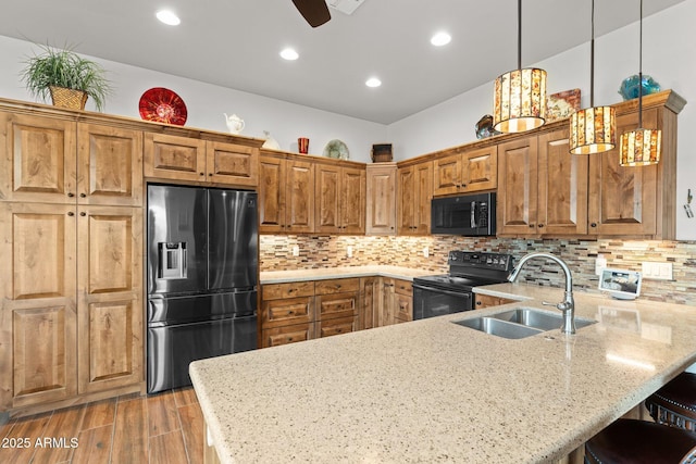 kitchen with a kitchen bar, black appliances, a sink, tasteful backsplash, and a peninsula