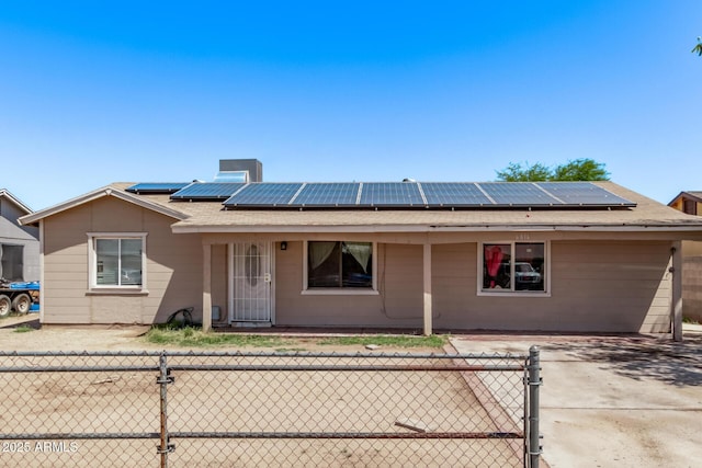 view of front of house with solar panels, fence, and a chimney