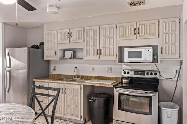 kitchen with stainless steel appliances, a sink, tasteful backsplash, tile countertops, and ceiling fan