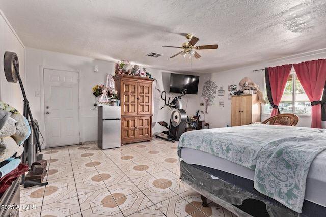 bedroom featuring freestanding refrigerator, light tile patterned flooring, a textured ceiling, and ceiling fan