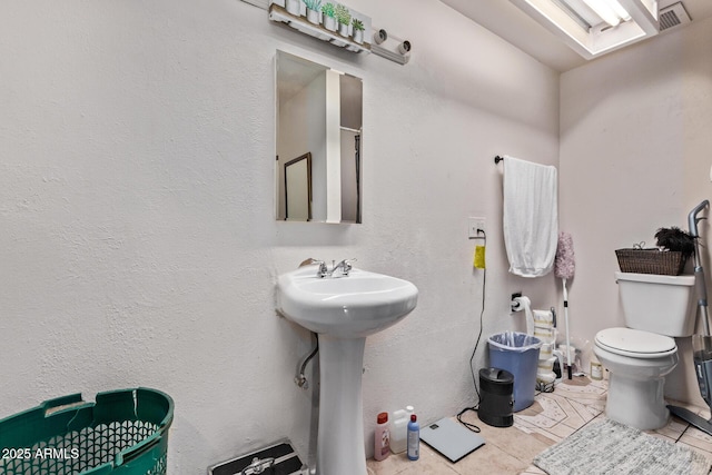 bathroom with toilet, tile patterned floors, and a sink