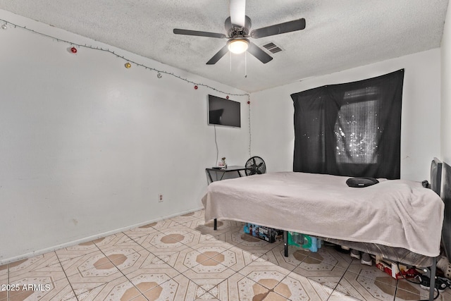 bedroom with a textured ceiling, light tile patterned flooring, ceiling fan, and baseboards