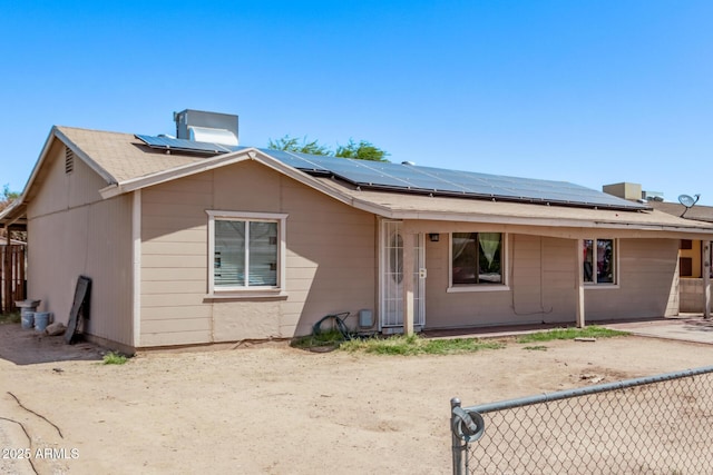 view of front of property featuring fence and roof mounted solar panels
