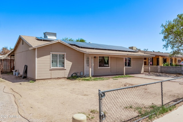 single story home featuring solar panels and a fenced backyard