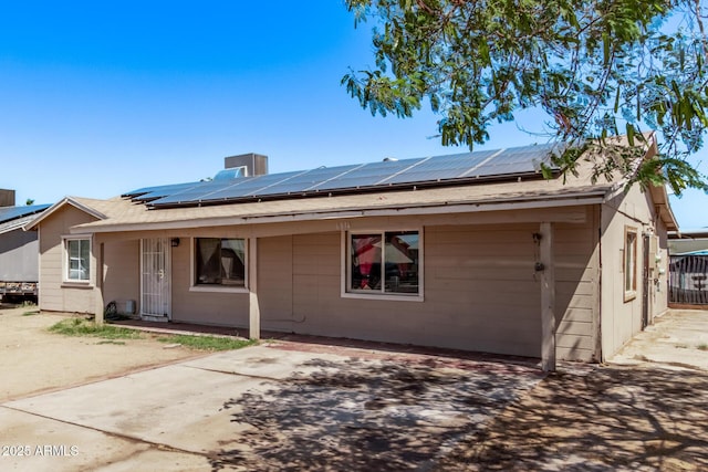view of front of home with concrete block siding and roof mounted solar panels