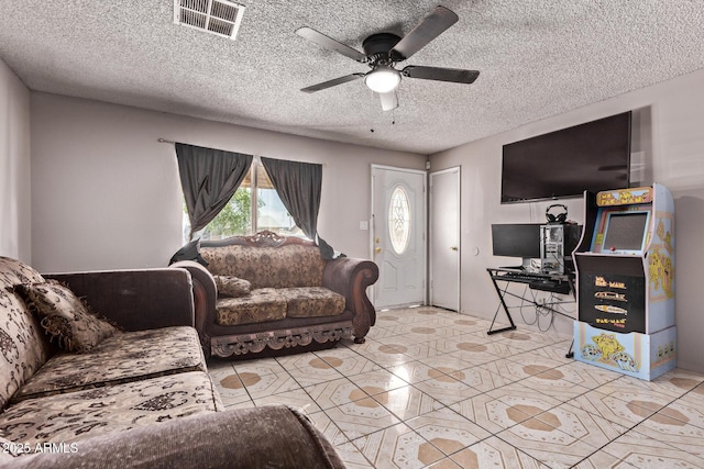 living area with a ceiling fan, tile patterned floors, and a textured ceiling