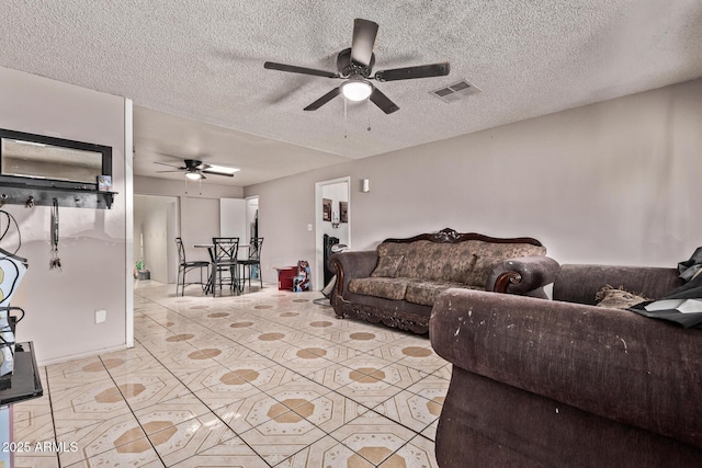 living area featuring ceiling fan, light tile patterned floors, and a textured ceiling