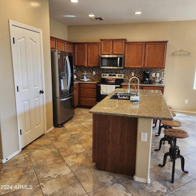 kitchen with backsplash, sink, light stone countertops, a kitchen bar, and stainless steel appliances