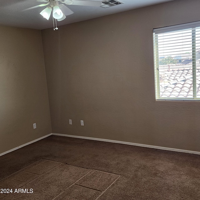 spare room with ceiling fan and dark carpet